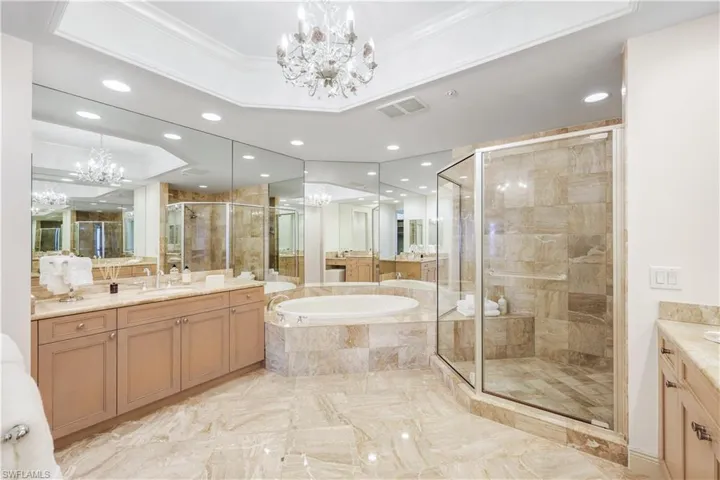 Bathroom featuring independent shower and bath, crown molding, a notable chandelier, and a tray ceiling