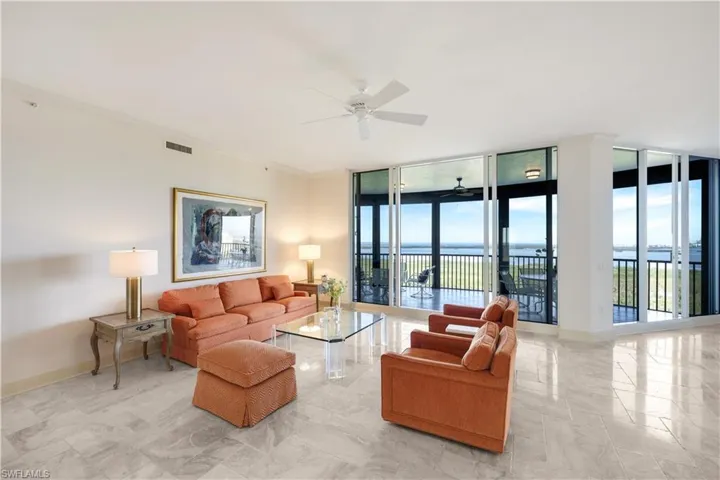 Living room featuring crown molding, floor to ceiling windows, and a water view