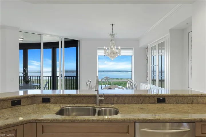 Kitchen with dishwasher, sink, hanging light fixtures, ornamental molding, and a water view