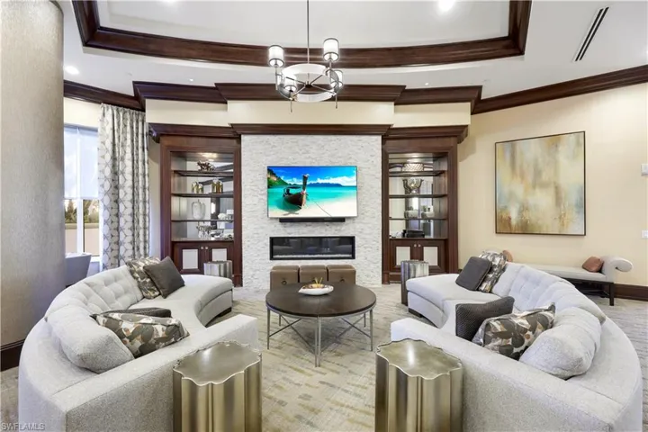 Living room with crown molding, a large fireplace, built in features, and a notable chandelier