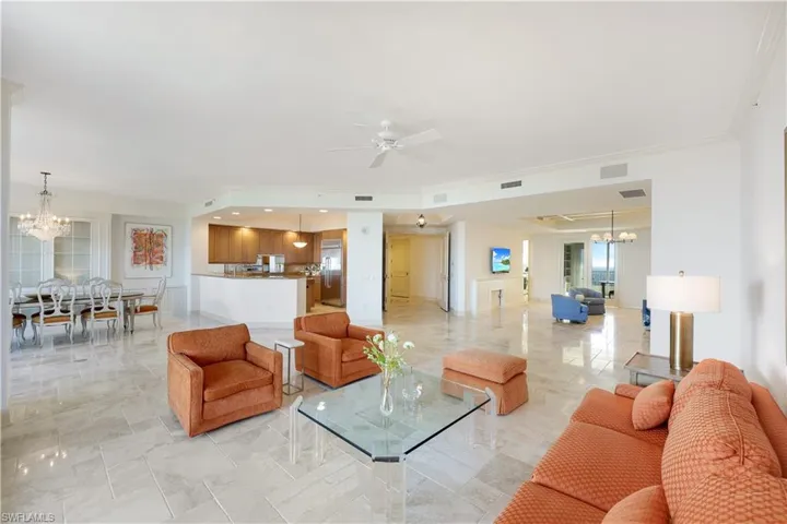 Living room featuring ceiling fan with notable chandelier and ornamental molding