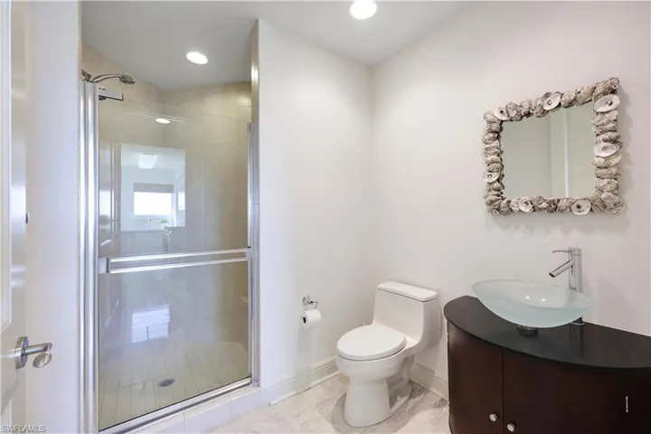 Bathroom with vanity, a shower with door, and toilet