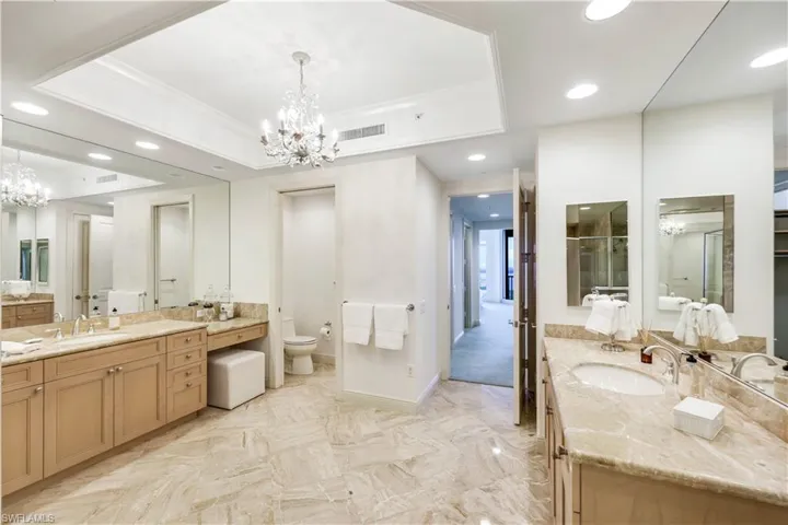 Bathroom featuring crown molding, a chandelier, vanity, a raised ceiling, and toilet