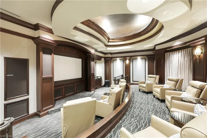 Carpeted home theater room featuring a tray ceiling and ornamental molding