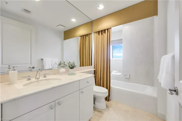 Full bathroom featuring shower / bathtub combination with curtain, vanity, toilet, and tile patterned flooring