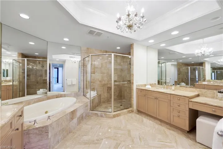 Bathroom featuring a raised ceiling, ornamental molding, vanity, and an inviting chandelier