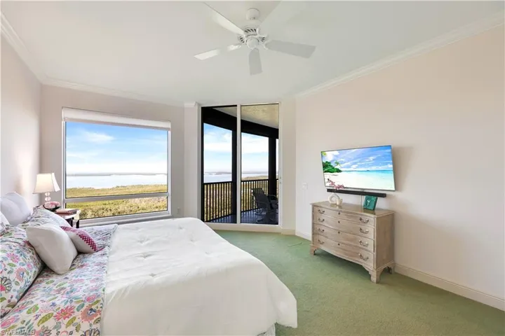 Bedroom featuring access to exterior, light colored carpet, ornamental molding, and ceiling fan