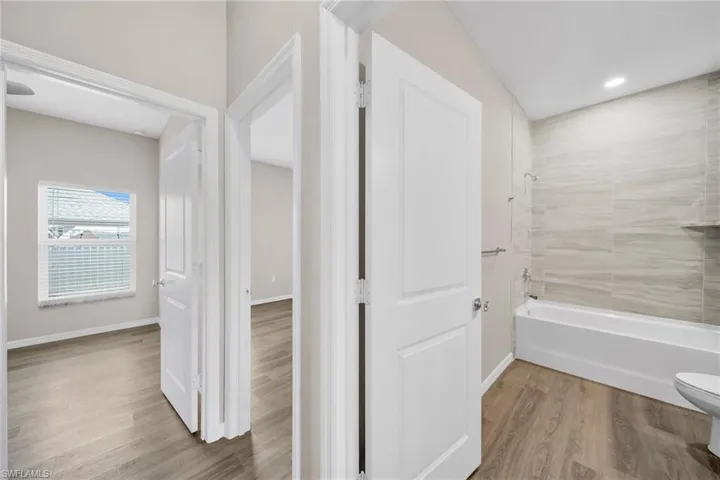 Full bathroom with wood finished floors, toilet, and baseboards