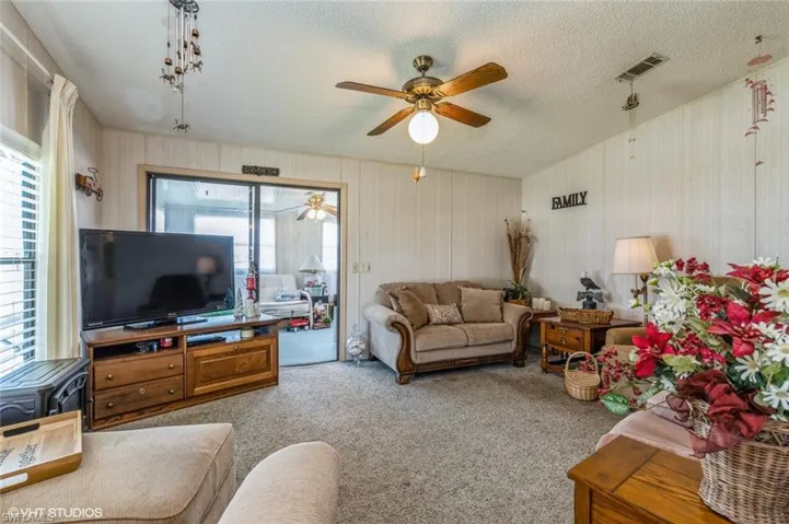 Carpeted living area with a ceiling fan and a textured ceiling