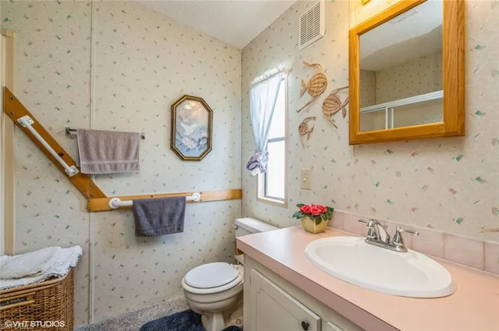 Full bath with a shower stall, vanity, wallpapered walls, and a textured ceiling