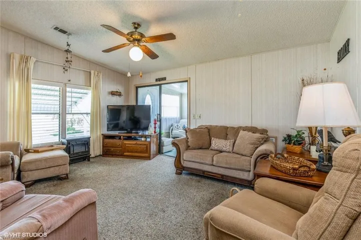 Carpeted living room with a textured ceiling and ceiling fan