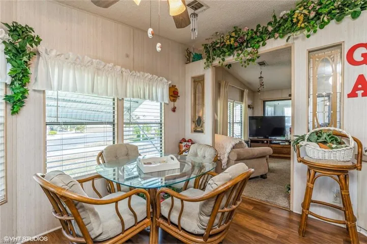 Dining space featuring ceiling fan, wood finished floors, a textured ceiling, and wallpapered walls