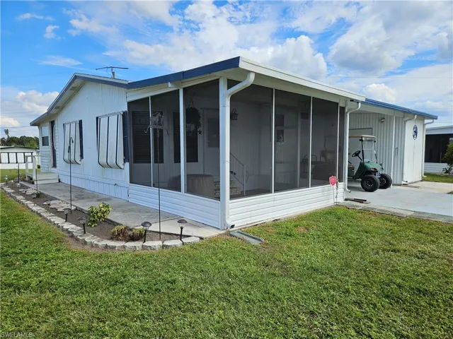 View of side of property with a sunroom and a lawn