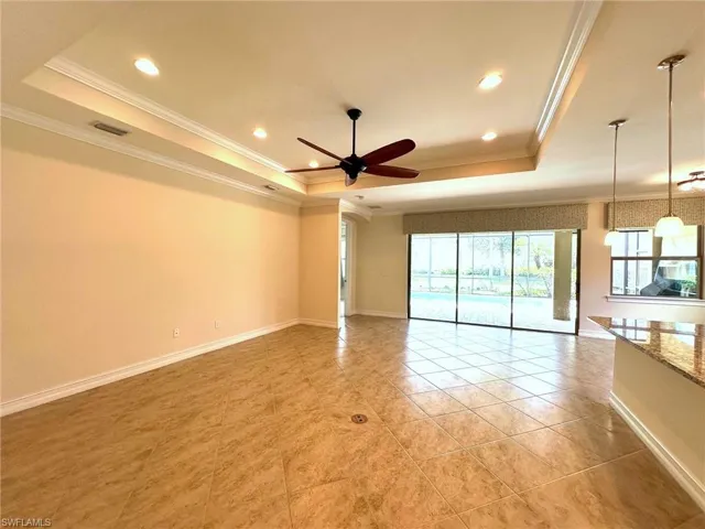 Empty room with a tray ceiling, ornamental molding, recessed lighting, light tile patterned flooring, and a ceiling fan