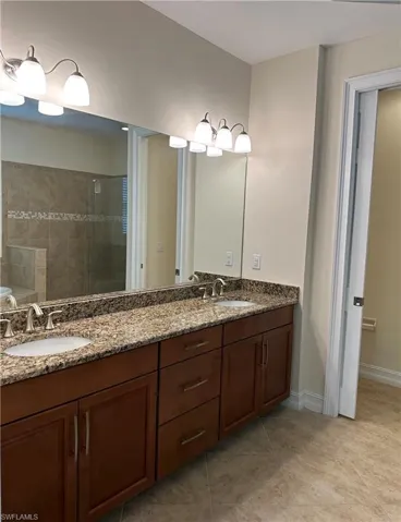 Bathroom featuring double vanity, a stall shower, and light tile patterned floors