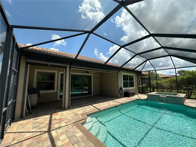 View of swimming pool, a lanai, a ceiling fan, a pool with connected hot tub
