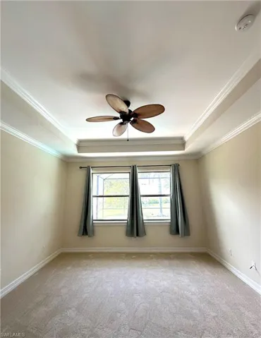 Master Bedroom with brand new carpet,  ornamental molding, a tray ceiling and a ceiling fan.