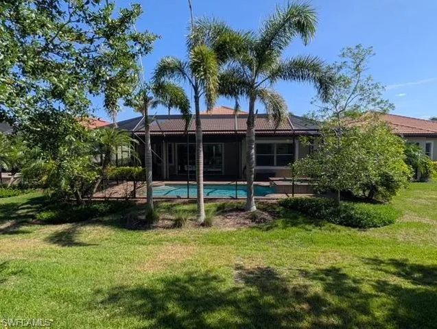 Rear view of property featuring a patio area, a lanai, a lawn, and a tile roof