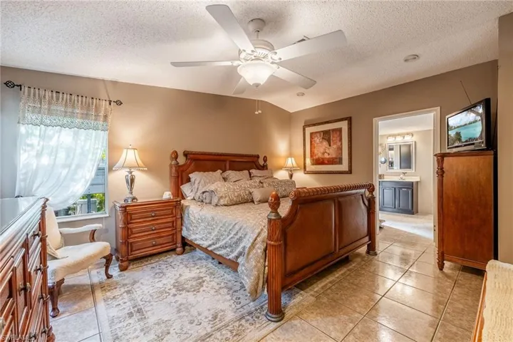 Bedroom with ceiling fan, a textured ceiling, and light tile patterned flooring