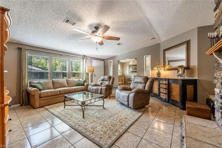 Living room featuring a ceiling fan, visible vents, and light tile patterned floors