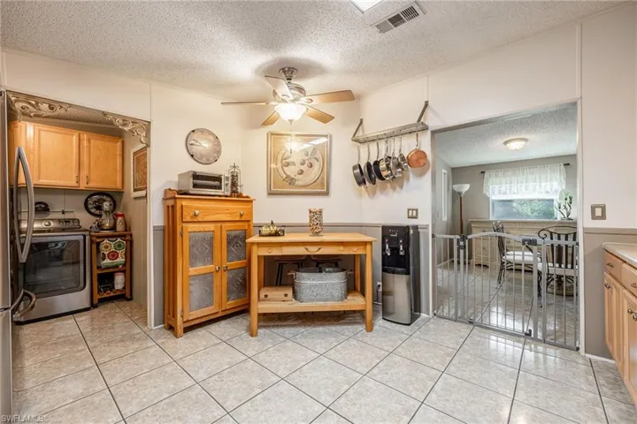 Kitchen featuring ceiling fan, light tile patterned floors, a textured ceiling, visible vents, and washer / dryer