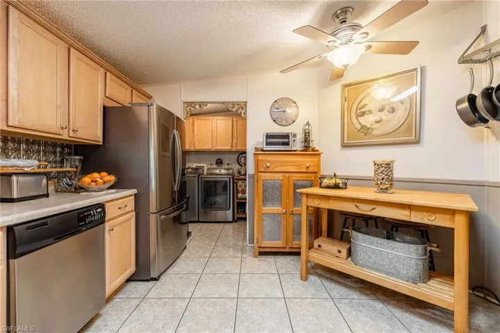 Kitchen featuring light tile patterned floors, a textured ceiling, light countertops, dishwasher, and washer and clothes dryer