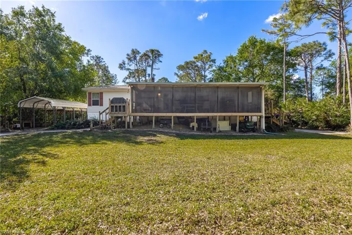 Rear view of property featuring a carport, a sunroom, and a yard