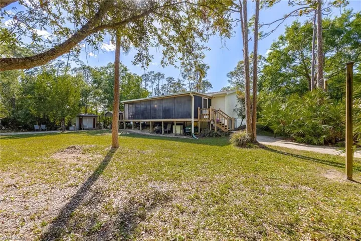 Back of property with stairs, a lawn, and a sunroom