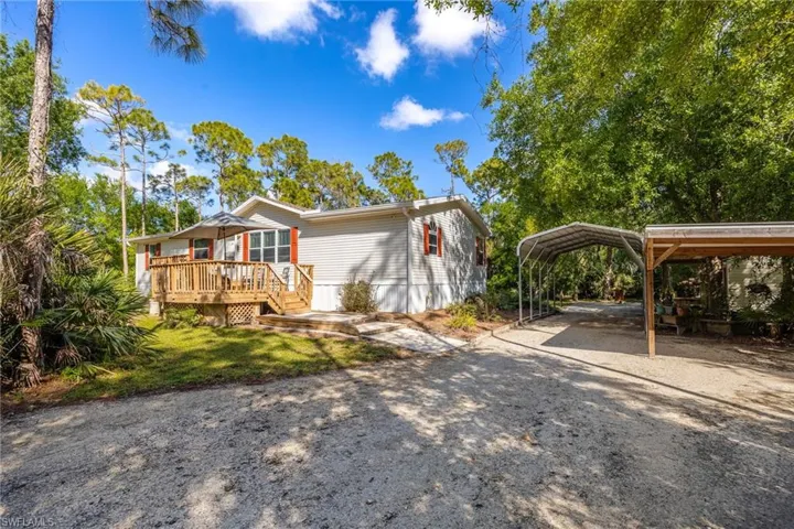 View of front facade featuring a deck, driveway, and a detached carport