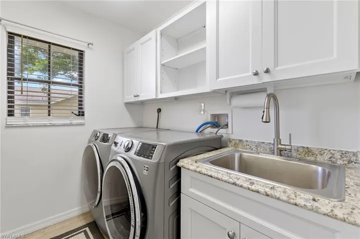 Clothes washing area featuring washer and dryer, cabinets, washer hookup, light hardwood / wood-style flooring, and sink