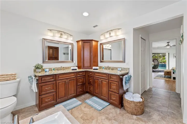 Bathroom featuring double sink, hardwood / wood-style flooring, oversized vanity, ceiling fan, and toilet