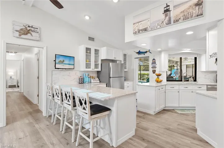 Kitchen with white cabinetry, light hardwood / wood-style flooring, appliances with stainless steel finishes, backsplash, and ceiling fan
