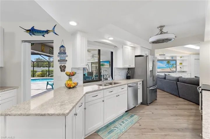 Kitchen with sink, white cabinets, tasteful backsplash, and light wood-type flooring
