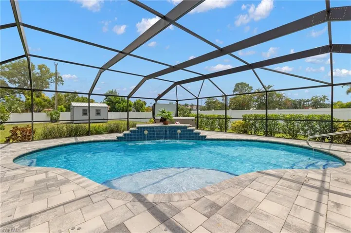 View of pool with a storage unit, glass enclosure, and a patio area