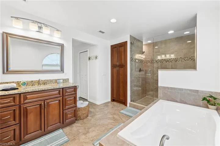 Bathroom with tile flooring, separate shower and tub, and vanity