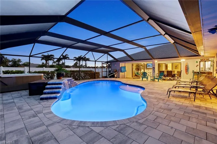 Pool at dusk with a patio, pool water feature, and a lanai