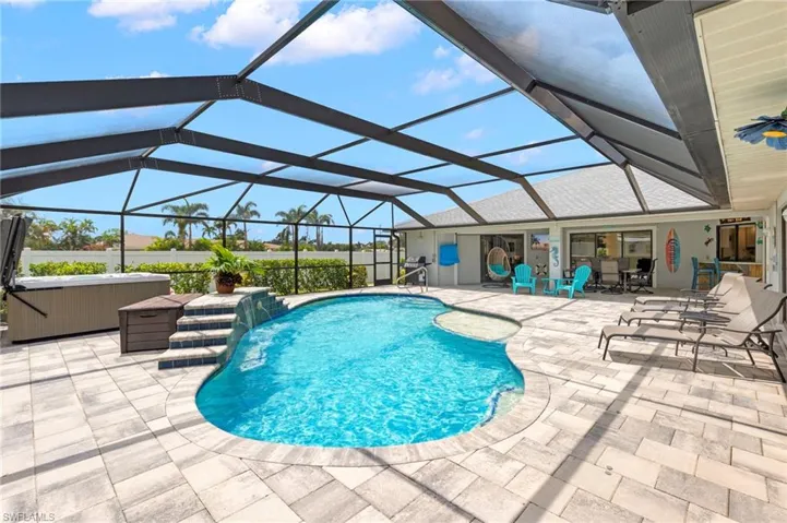 View of pool with a hot tub, a lanai, a patio area, and pool water feature
