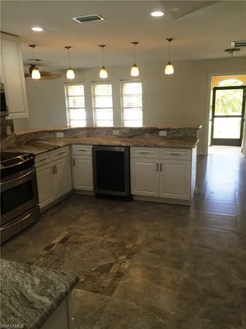 Kitchen with white cabinets, appliances with stainless steel finishes, pendant lighting, quartz countertops, and recessed lighting