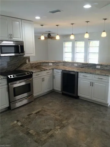 Kitchen featuring white cabinetry, appliances with stainless steel finishes, backsplash, hanging light fixtures, and recessed lighting