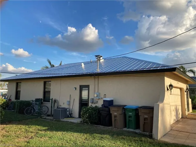 Back of property featuring stucco siding, a garage, a patio area, and a metal roof
