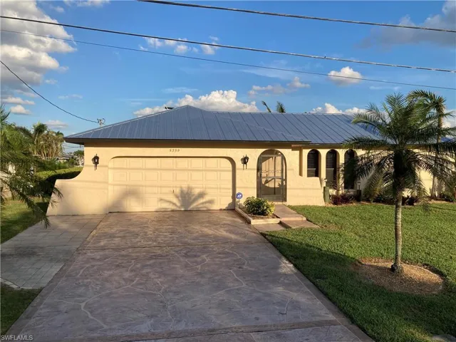 View of front of property with stucco siding, a front lawn, concrete driveway, and an attached garage