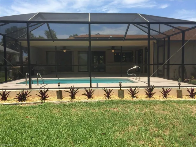 Back of property with a lanai, a sunroom, and an outdoor pool
