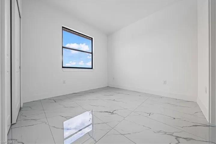 Unfurnished room with baseboards and light marble finish floors