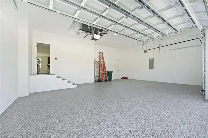 Spacious garage featuring a light-toned speckled epoxy floor coating, white painted walls, and a visible garage door mechanism