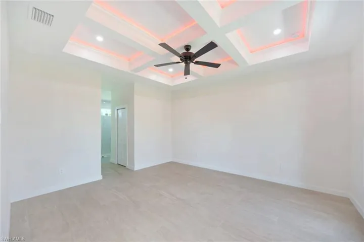 Spacious room featuring a decorative tray ceiling with recessed lighting and subtle accent lighting