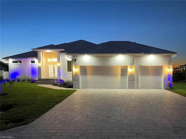 Modern facade featuring a dark metal roof, white stucco exterior, and a paver driveway