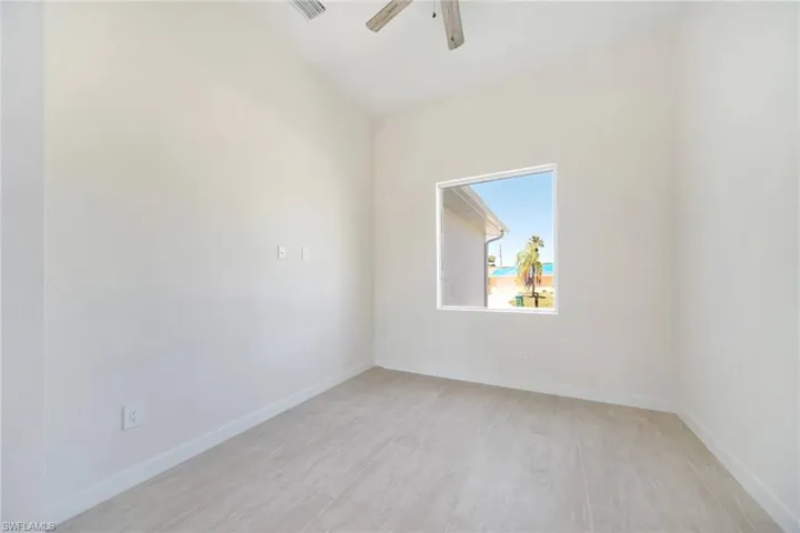 Room featuring a single window, light-toned tile flooring, white baseboards, and a ceiling fan