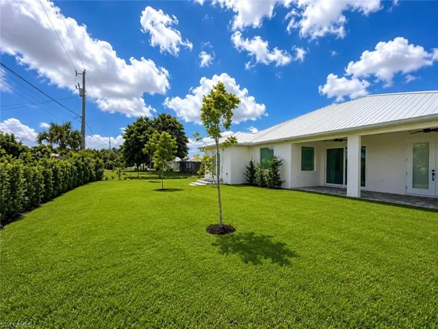 Expansive green lawn with a white exterior residence featuring a metal roof