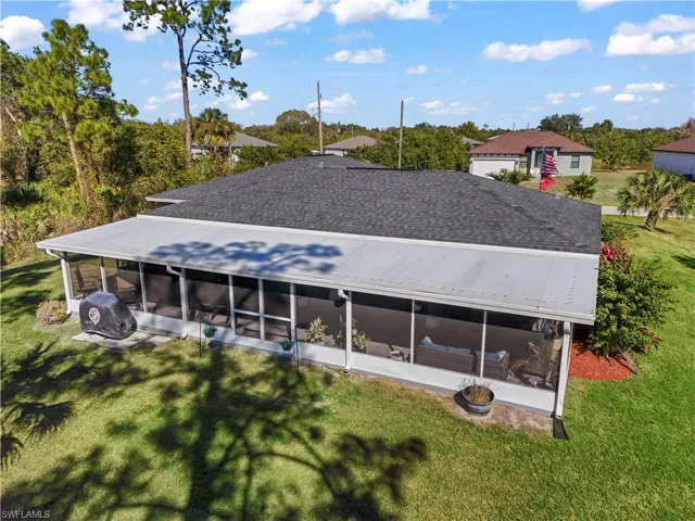 Back of house featuring a yard, a sunroom, and a shingled roof