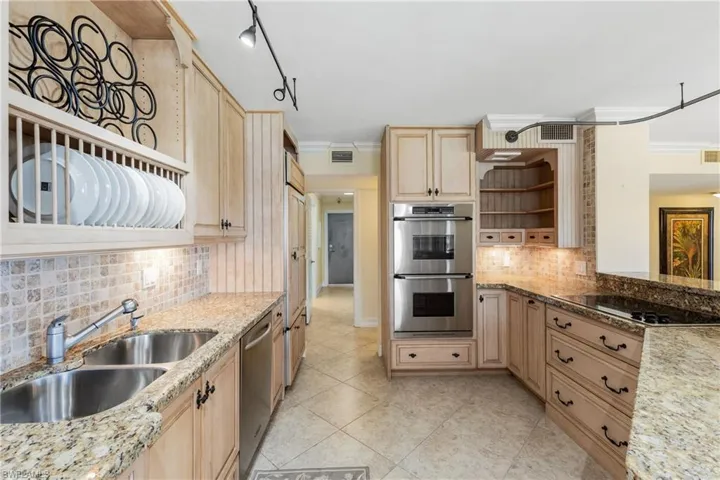 Kitchen with ornamental molding, appliances with stainless steel finishes, backsplash, track lighting, and light brown cabinets